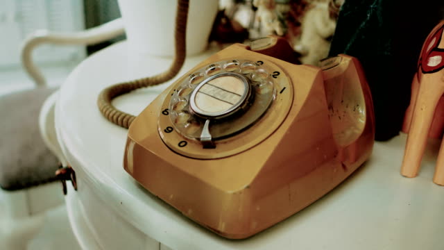 4K. people use finger dialing an retro rotary vintage style telephone. film dye for vintage tone. old telecommunication technology