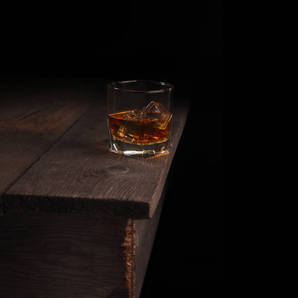 Ice cubes float in a glass with whiskey and blow bubbles