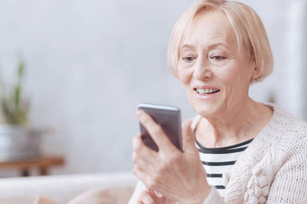 istock Pretty excited elderly woman texting on phone 867998546