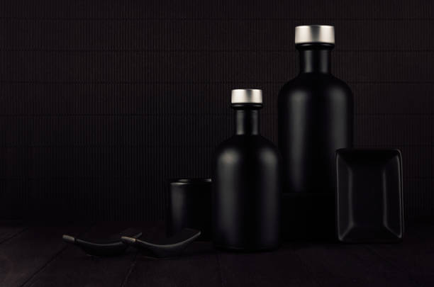 Dark black minimalist interior. Blank black cosmetics bottles on dark wood board, mock up. Noir elegant home decor for advertising, designers, branding identity, cover.