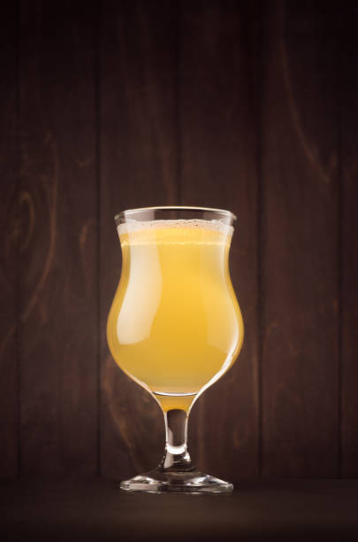 Tulip beer glass with muddy weizen on dark wood board, vertical. Template for advertising, design, branding identity, restaurant menu, cover.