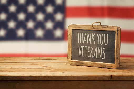 Fondo del día de los veteranos con pizarra sobre la mesa de madera y bandera de Estados Unidos photo