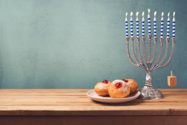 istock Hanukkah background with menorah and sufganiyot on wooden table 868015538
