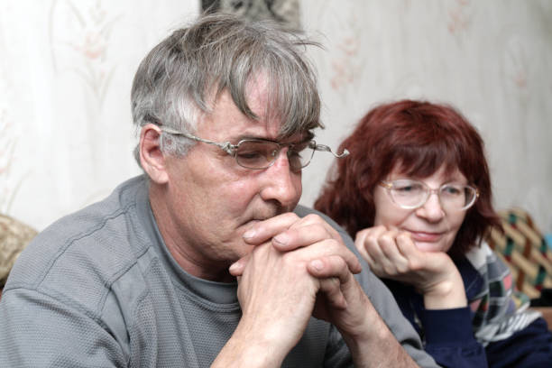 Closeup of an adult married couple in their 70s holding hands.