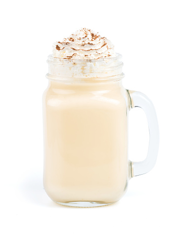 Eggnog with whipped cream and cinnamon in mason jar isolated on white. Homemade eggnog in mason jar isolated with clipping path
