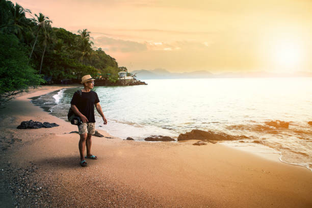 istock traveling man and dslr camera walking on sand beach against sunset sky 868026414