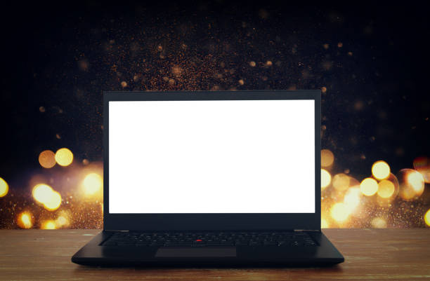 istock open laptop with white screen on wooden table in front of abstract glitter background 868029202