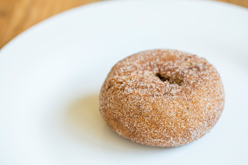 Pumpkin sugar donut doughnut on a white plate wood background