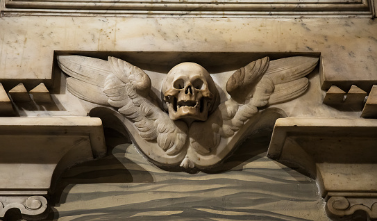 Marble skull and wings on the wall in the Catholic church in Rome, Italy.