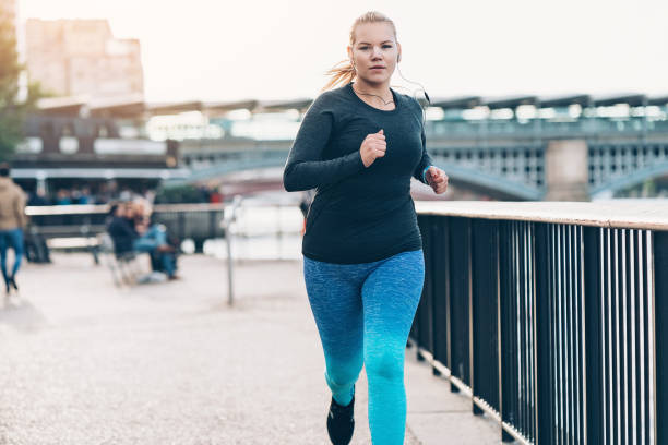 young woman jogging in the morning - overweight women serious people imagens e fotografias de stock