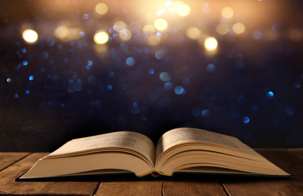 istock image of open antique book on wooden table with glitter background 868036868