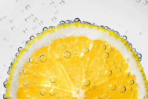 Lemon slice in carbonated soda fizz water with bubbles on white background