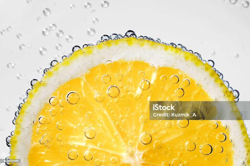 Lemon slice with bubbles Lemon slice in carbonated soda fizz water with bubbles on white background Carbonated Stock Photo