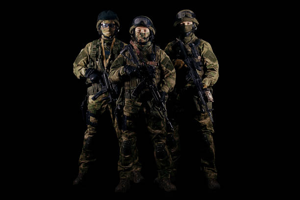 istock Three soldiers in uniform with a weapon in their hands are looking menacingly. 868044724