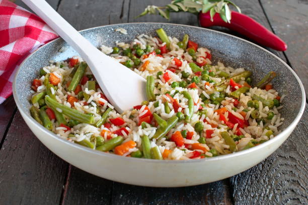 riso cotto con verdure e olio d'oliva in padella. - flavored rice foto e immagini stock