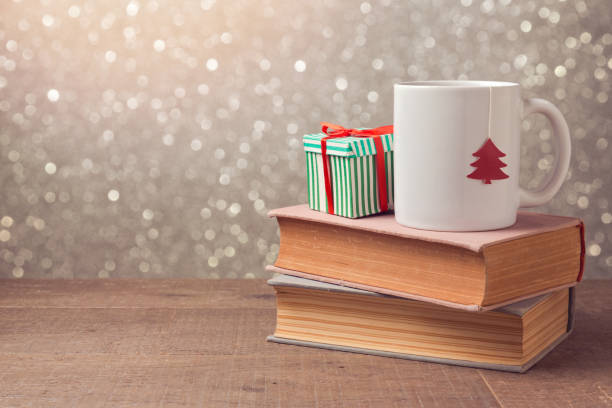 istock Christmas celebration with cup and gift box on books over bokeh background 868049286