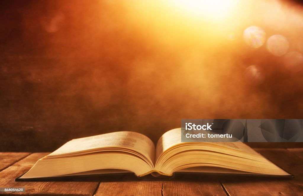 image of open antique book on wooden table with glitter background Bible Stock Photo