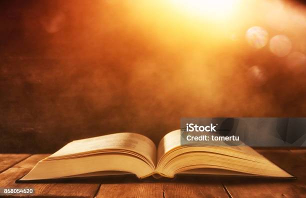 Image Of Open Antique Book On Wooden Table With Glitter Background Stock Photo - Download Image Now