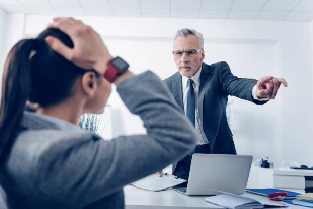 Angry boss outing his young office worker Get out of here. Selective focus on an extremely mad chief in glasses looking at his scared female employee with hands on the head and pointing toward a door while asking her to leave the office. bossy stock pictures, royalty-free photos & images