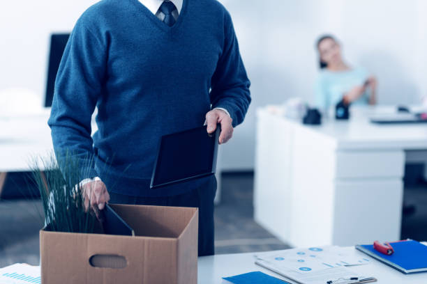 Close up of mature man packing office supplies in box Leaving my work. Scaled up shot of an adult office worker in formal attire standing next to his table and packing his personal stuff in a paper box after being retired. former stock pictures, royalty-free photos & images