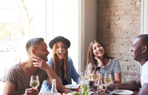 laughing friends having wine and a meal together - mirth imagens e fotografias de stock
