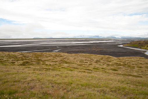 Remote volcanic lands somewhere in Iceland mainland, surrounded by vibrant green bushes and volcanic lands. Volcanic rock formations, small mountains, black grey volcanic rock. No people.