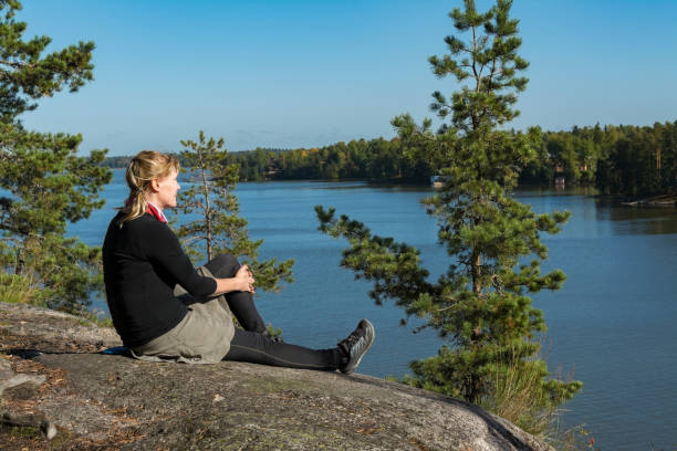 istock Woman sitting on high cliff and looking for lake view 868072054
