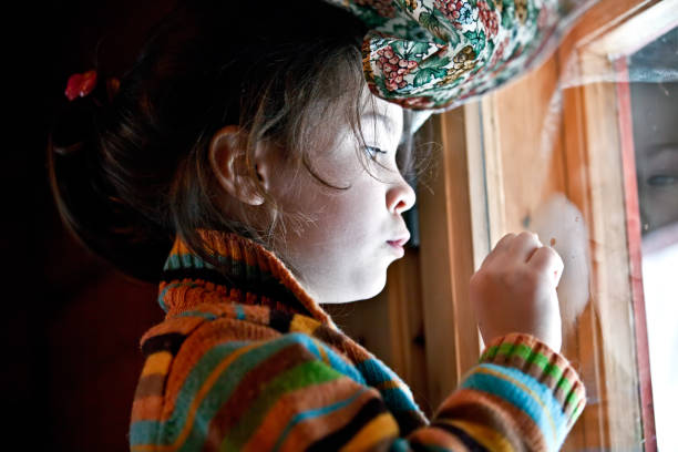 istock A cute little girl draws on the window. 868080734