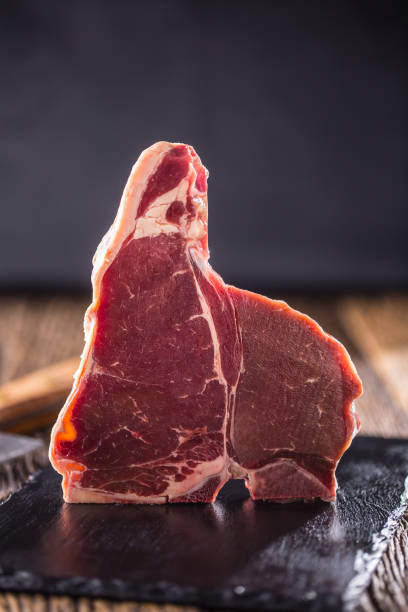 istock Beef steak T-bone. Raw beef steak T-bone on slate board with butcher and fork 868087314