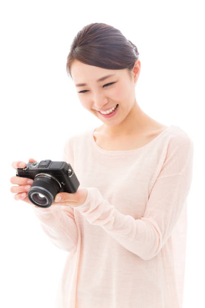 A young Asian woman holding a camera and smiling