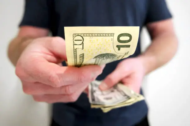 Photo of Man handing out american ten dollar bill