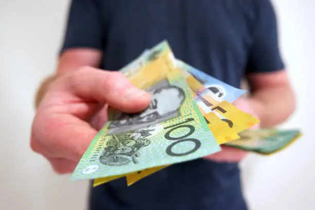 Photo of Man handing out hundreds and fifties Australian dollar bills