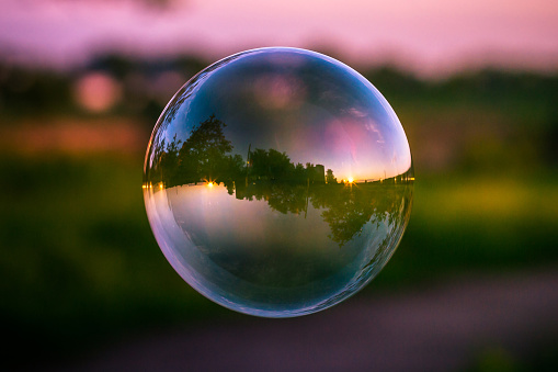 Reflection of the colorful sunset sky in the soap bubble