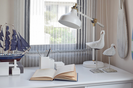 work table with lamp,pencils and books in working room