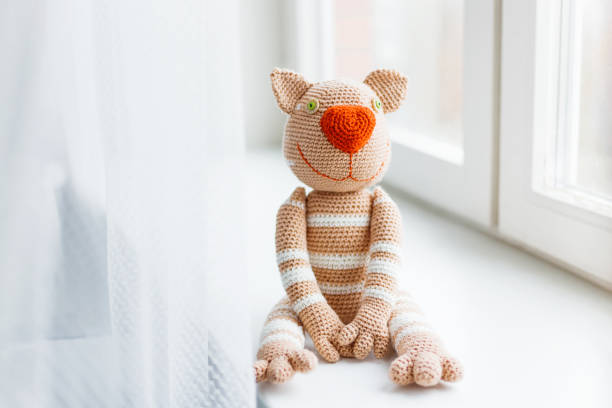 istock Handmade knitted toy cat. Beige paws with white stripes. 868119992