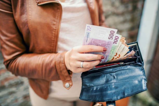 la donna rivede i suoi soldi sul suo lavoro. l'imprenditrice sta prendendo soldi dal portafoglio. mani di donna che tengono banconote europee. giovane donna shopper prendendo i soldi dal portafoglio per strada - focus on foreground tax close up finance foto e immagini stock