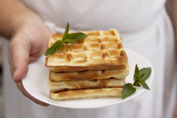 a stack of freshly baked wafers in the chef's hands for men, close-up, retro toning - brussels waffle belgian waffle people imagens e fotografias de stock