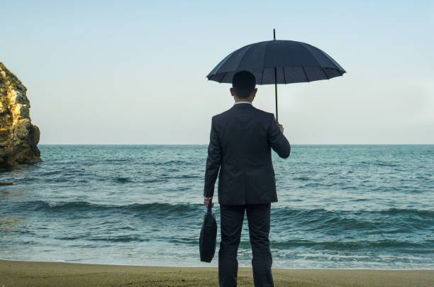 istock Businessman with umbrella on the beach 868143266