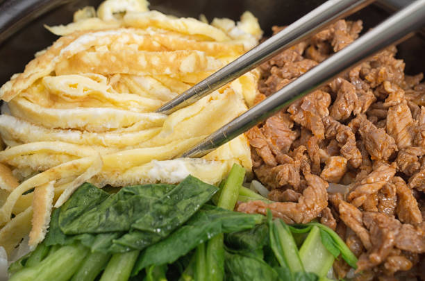 Closeup shot of Korean bibimbap dish with metallic chopsticks