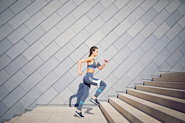 menina é runing sobre as escadas da cidade e ouvir música - sports music - fotografias e filmes do acervo