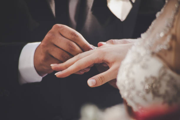 istock Groom Putting Ring On Bride's Finger 868184400