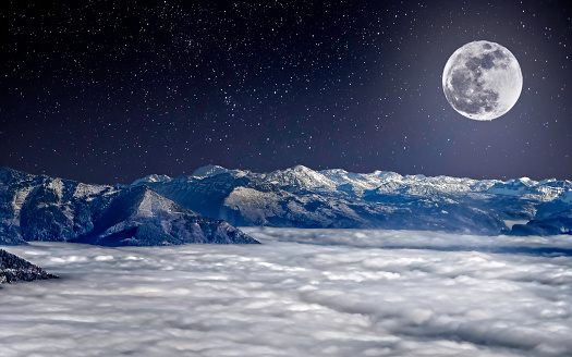 The full moon over snowy Alps in the night, above clouds, under the starry sky