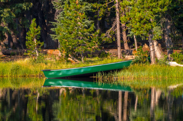 Canoe on the edge of the water on a reflective lake stock photo