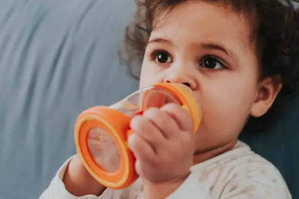 Stock photo of 18 month old baby girl drinking from her baby bottle.