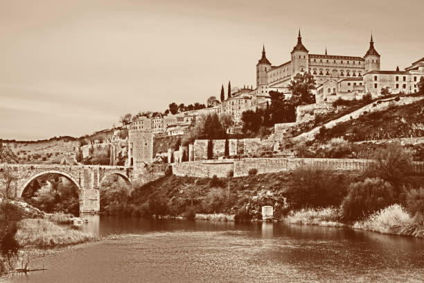 toledo con fortezza alcazar, ponte di alcantara e fiume tajo, spagna - alcantara bridge foto e immagini stock