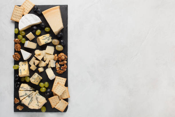 白ブドウ、クルミ、クラッカーと石ボードの上のチーズの盛り合わせ。明るい背景にロマンチックなデートのための食糧。トップ ビュー - 698 ストックフォトと画像