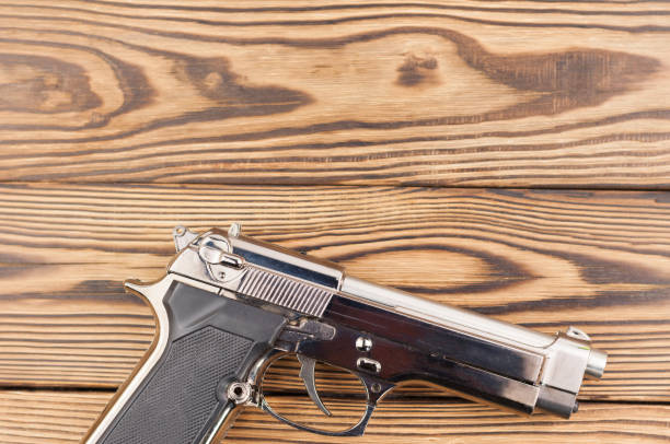 istock Single metal and glossy pistol on old rustic wooden weathered planks 868206874
