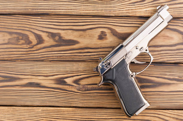 istock Single metal and glossy pistol on old rustic wooden weathered planks 868206888