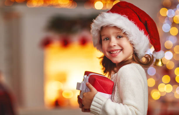 felice ragazza bambina ridendo con regalo di natale a casa - christmas child foto e immagini stock
