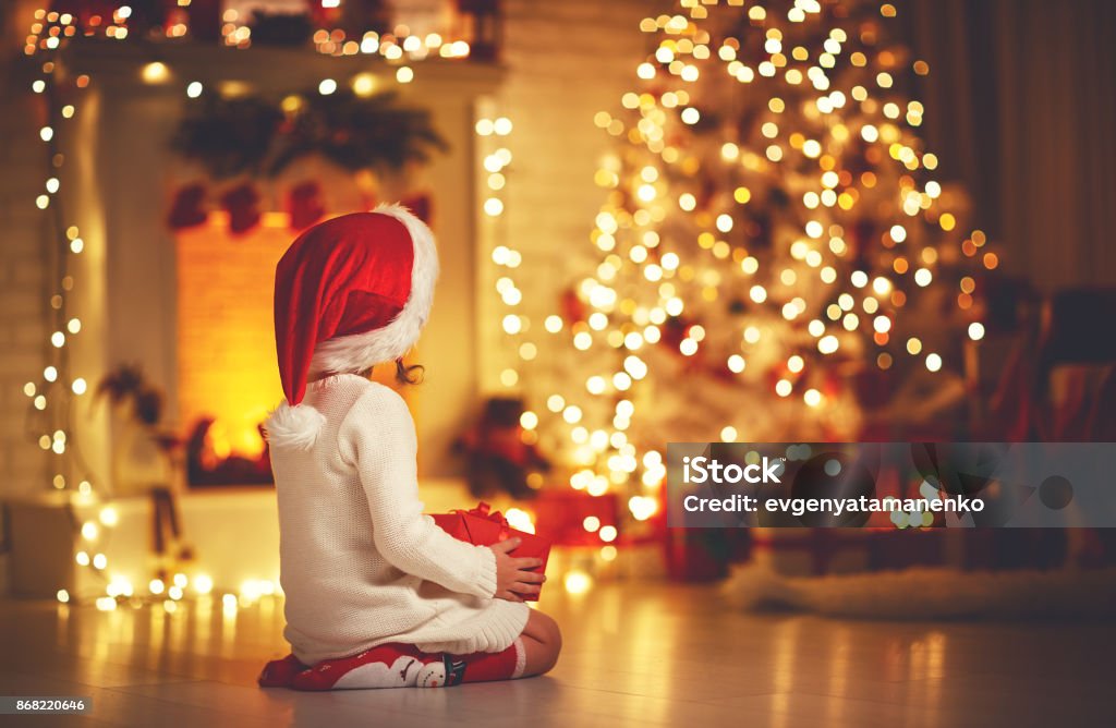 muchacha del niño sentarse frente a árbol de Navidad en la Nochebuena - Foto de stock de Navidad libre de derechos
